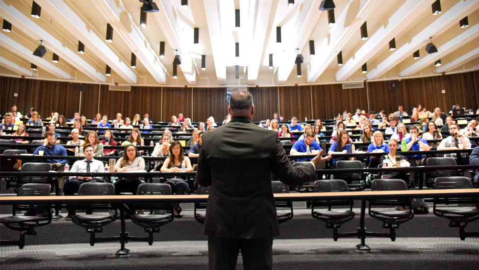 Person presenting to an auditorium of students