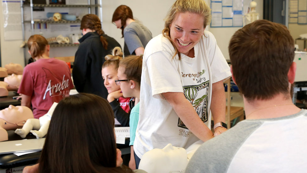 Students practicing physical therapy on dummy bodies