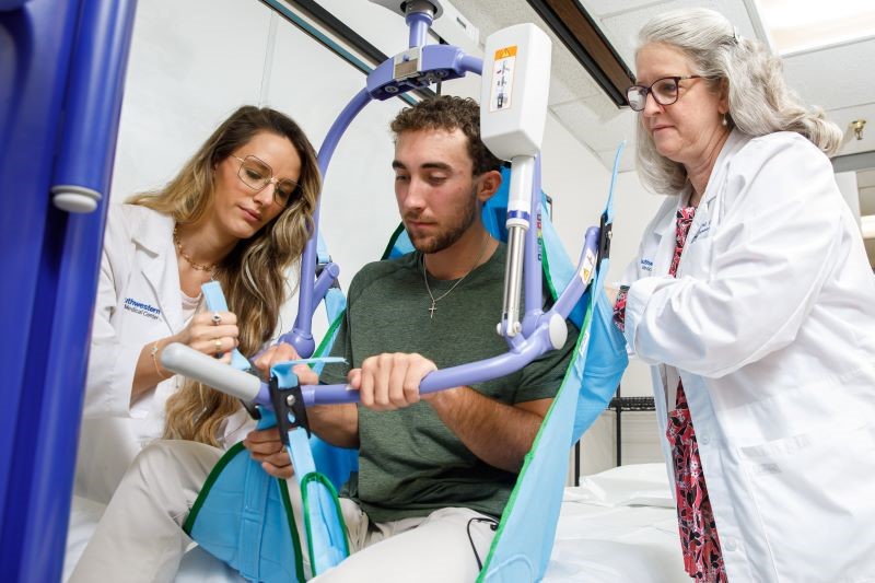 two female doctors working with a male patient