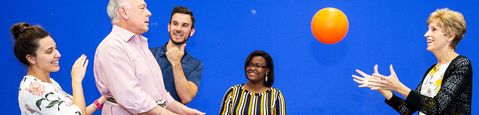 Physical therapists work with a man as he tosses a ball to a woman