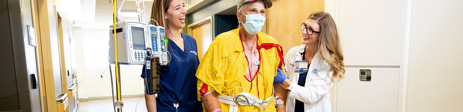 Physical therapy students help a male patient walk