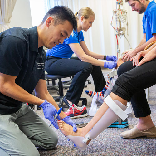 A man adjusts an orthotic on a woman's leg