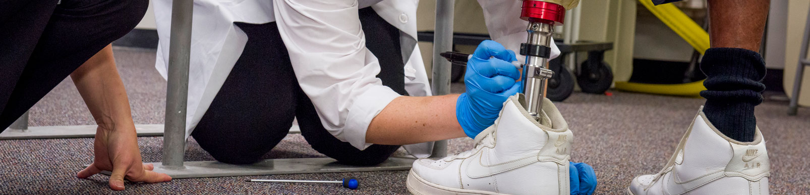 A woman draws a line with a marker on a left leg prosthetic