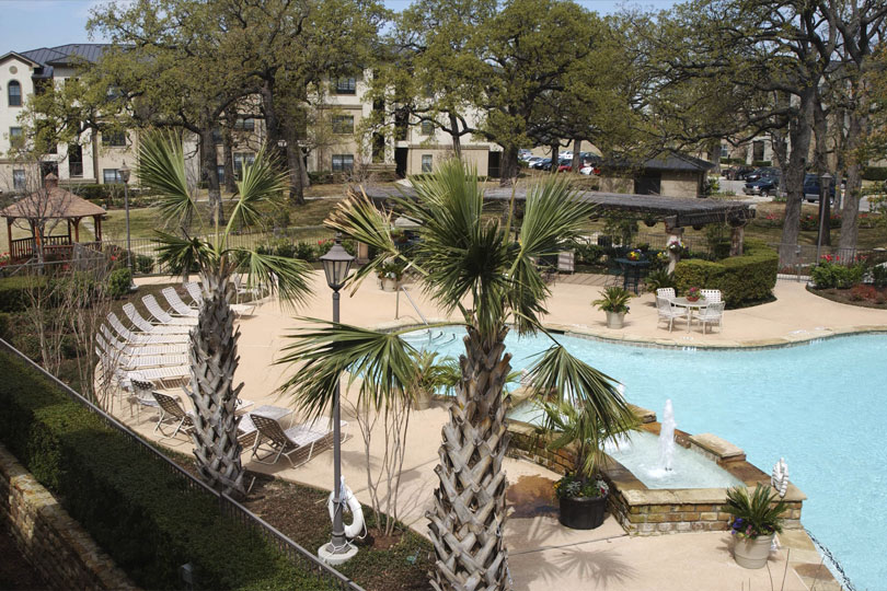 Medical Park Apartments with a pool and plan trees on the side