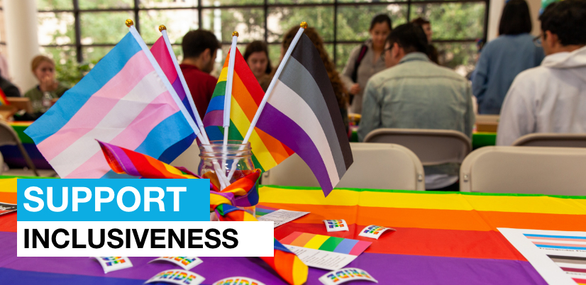 A rainbow table cloth and rainbow PRIDE flags on a table and the message Support Inclusiveness