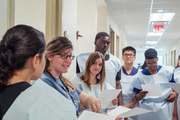 A group of students go over handout material with a medical school faculty member