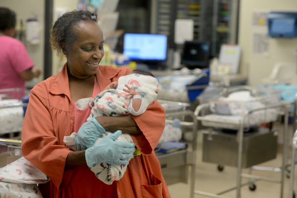 A Black woman holds a newborn baby in the Parkland nursery
