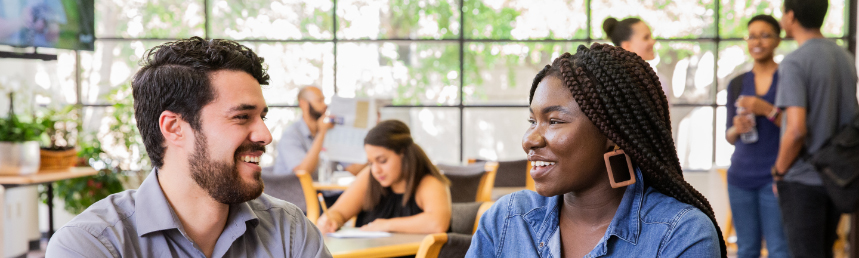 A Black woman and a white man smile as they talk