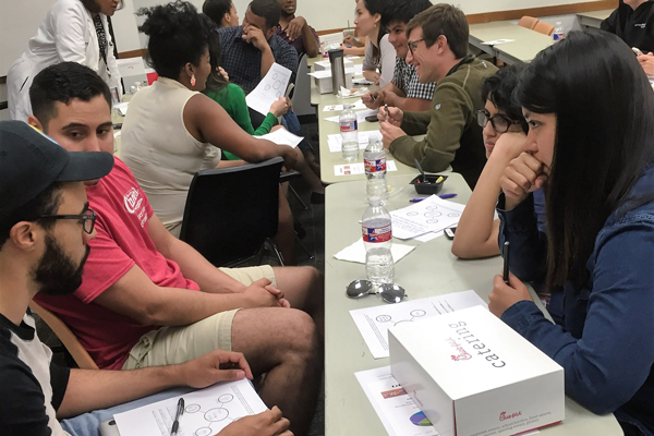 Male and female learners sit at a row of tables