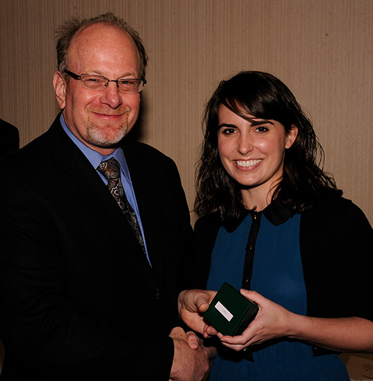 Man handing woman a small box and shaking hands