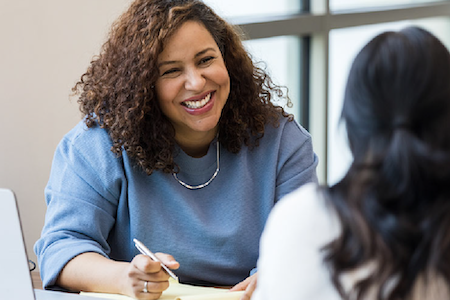 woman smiling holding ink pen consulting another woman