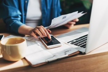 unidentified person sitting at a desk with hand extended on a calculator
