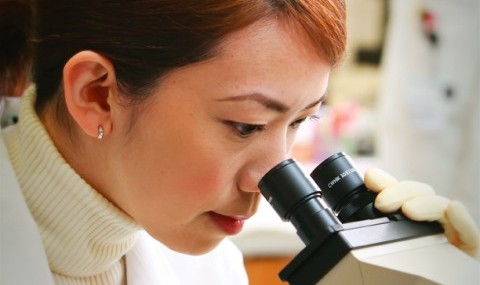 A woman looks into a microscope