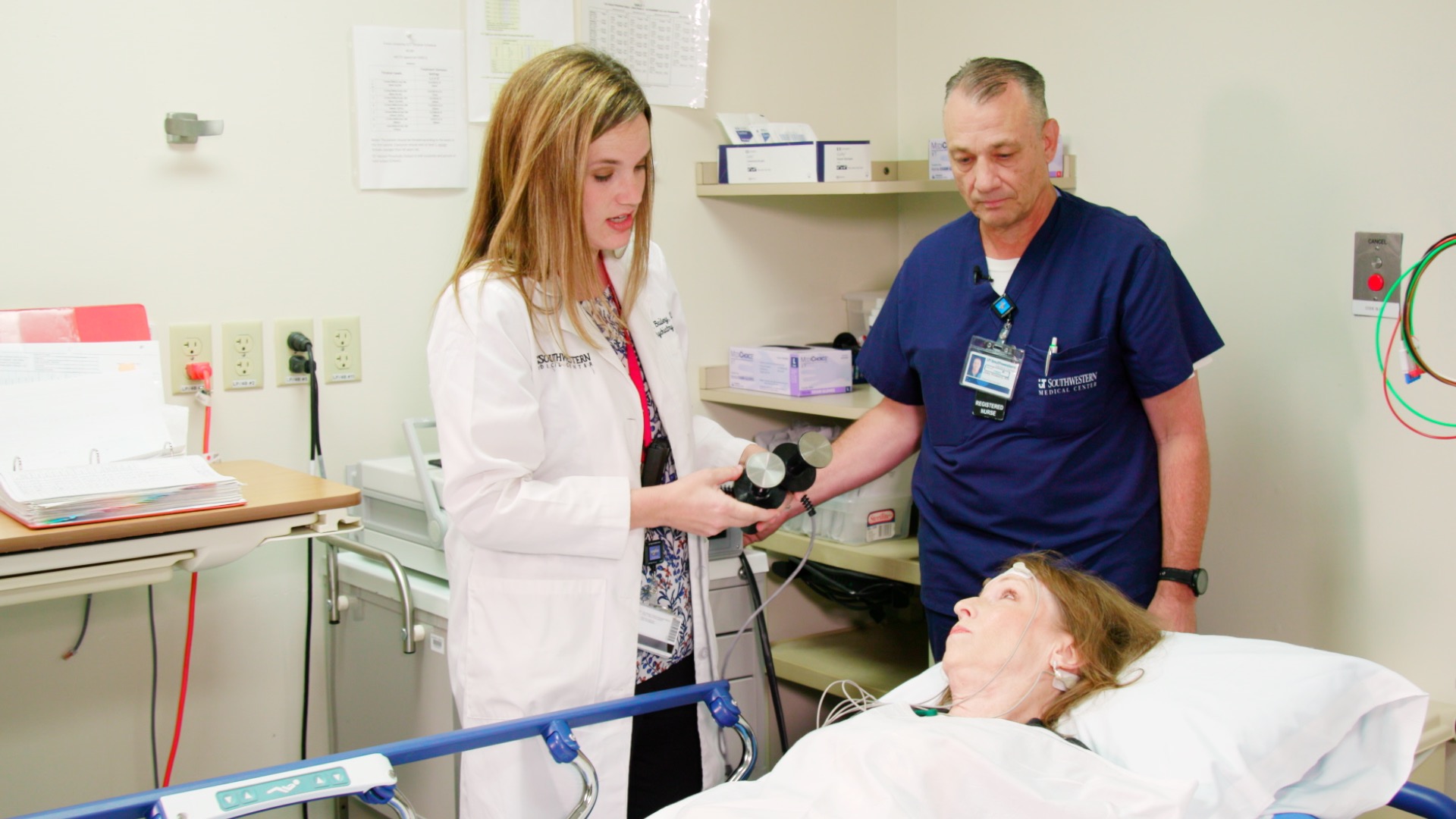Janice Blake lays on the bed as Dr. Kala Bailey (left) prepares to simulate an ECT treatment. UT Southwestern is enrolling participants for a clinical trial testing ECT and an alternative magnetic treatment for major depression. Dr. Bailey