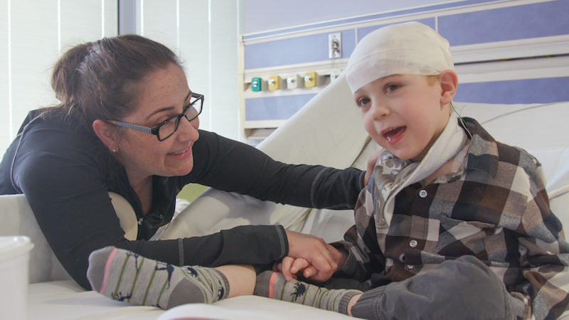 Joseph Hann laughs as his mother, Gina, reads a children’s book to him during a visit to UT Southwestern.