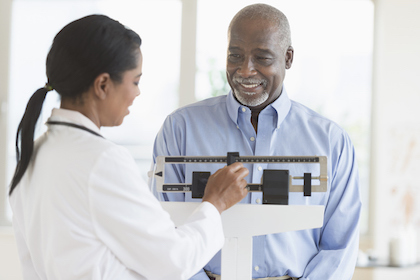 Healthy-weight man being weighed on a scale by a doctor