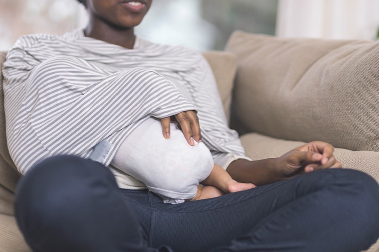 A baby breastfeeds under its mother's shirt