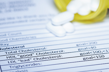 A printed report of a cholesterol test with white pills lying o nthe top right corner