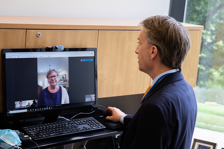 A male physician speaks with a woman through a computer