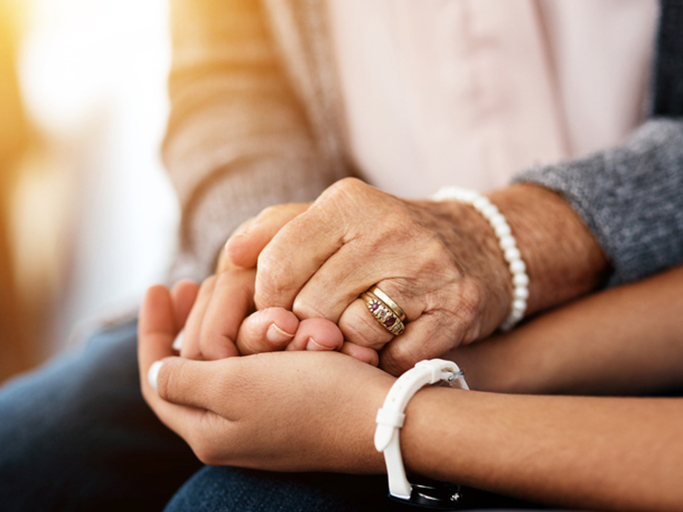 An older woman's hands held in the palm of a younger woman's hands