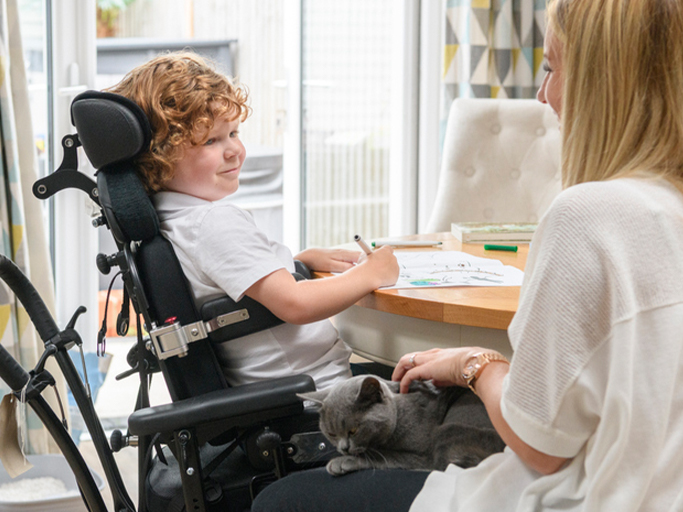 Boy in a wheelchair writes at a desk