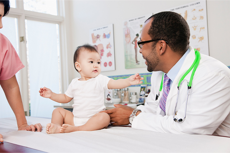 A baby reaches out to a male doctor