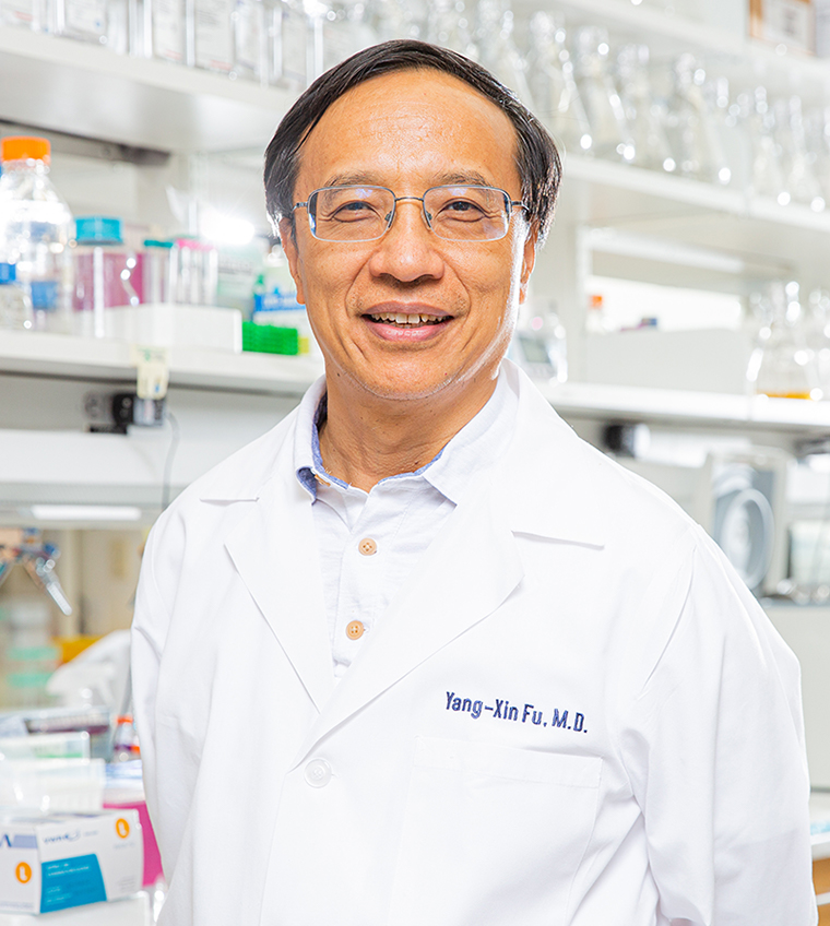 A man with black hair, glasses, wearing lab coat