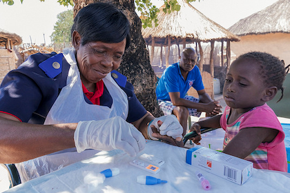 A nurse sticks a small girl's finger to do a blood test in Namibia, Africa