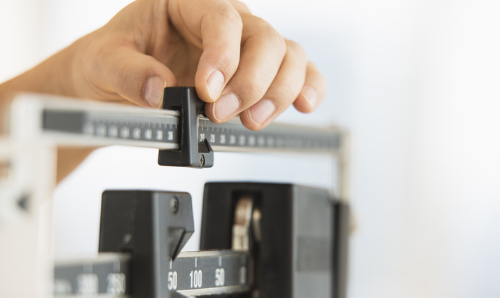 A person's hand adjusting a weight scale