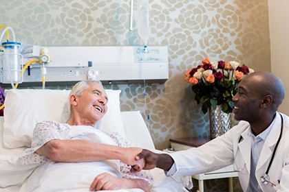 A white male patient shakes hands with a Black male doctor