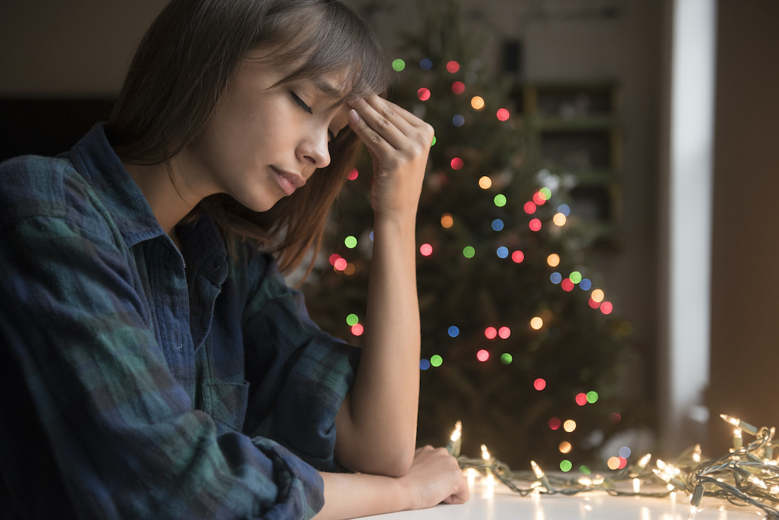 woman with headache near Christmas tree