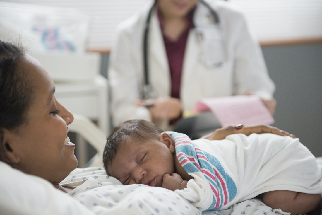 pediatrician examining newborn baby and mother at hospital