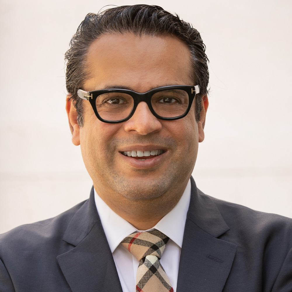 man with glasses and gray suit, yellow striped tie