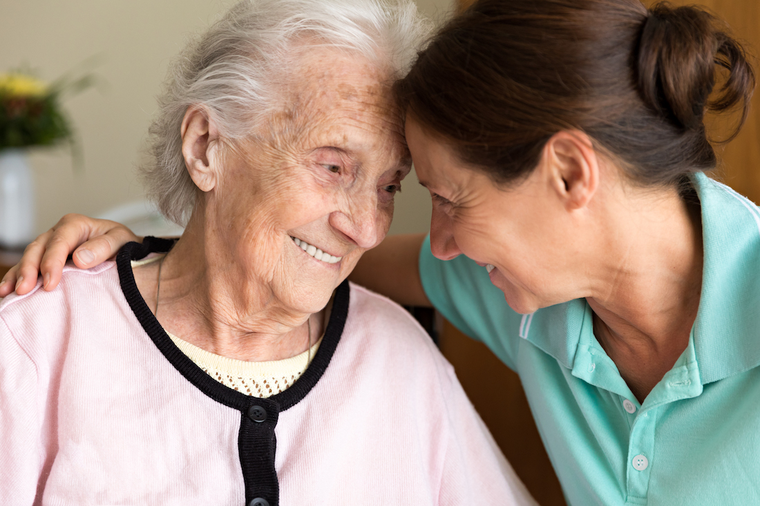 Elderly woman hugging younger woman