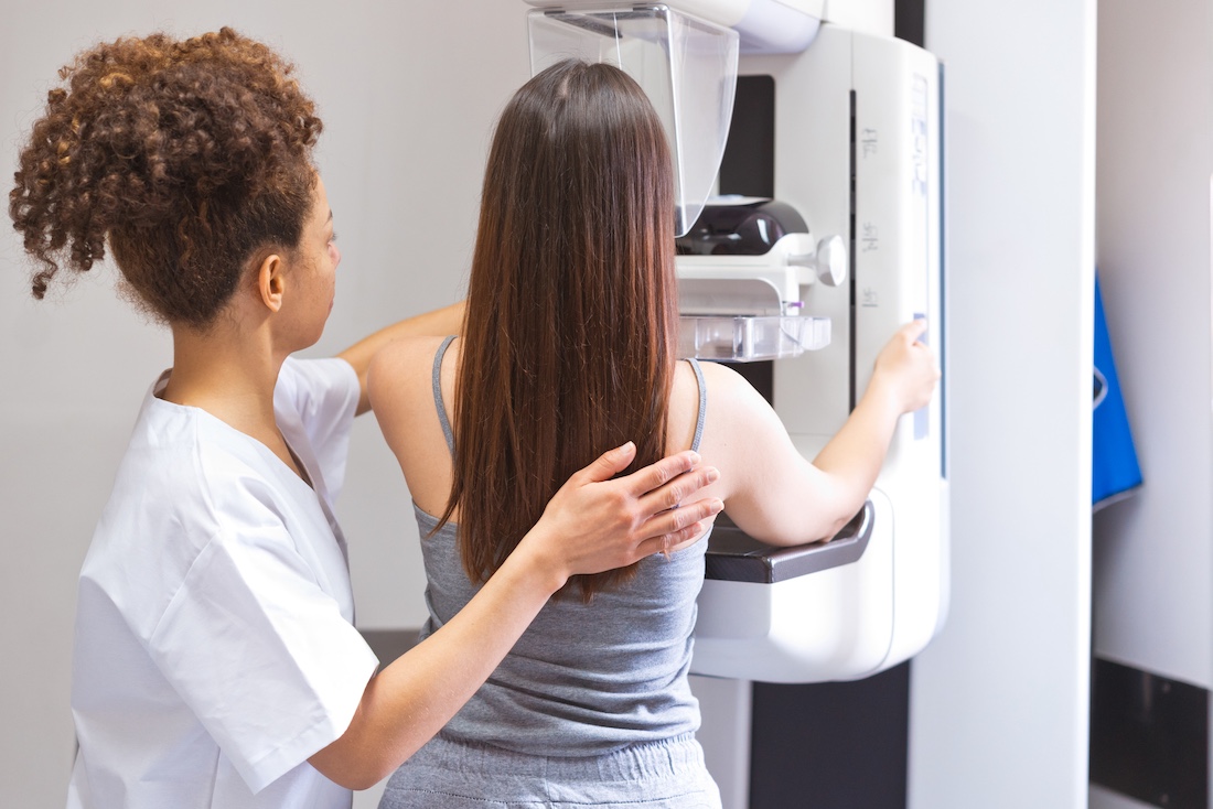 Female doctor talking to patient during Mammography test in examination room