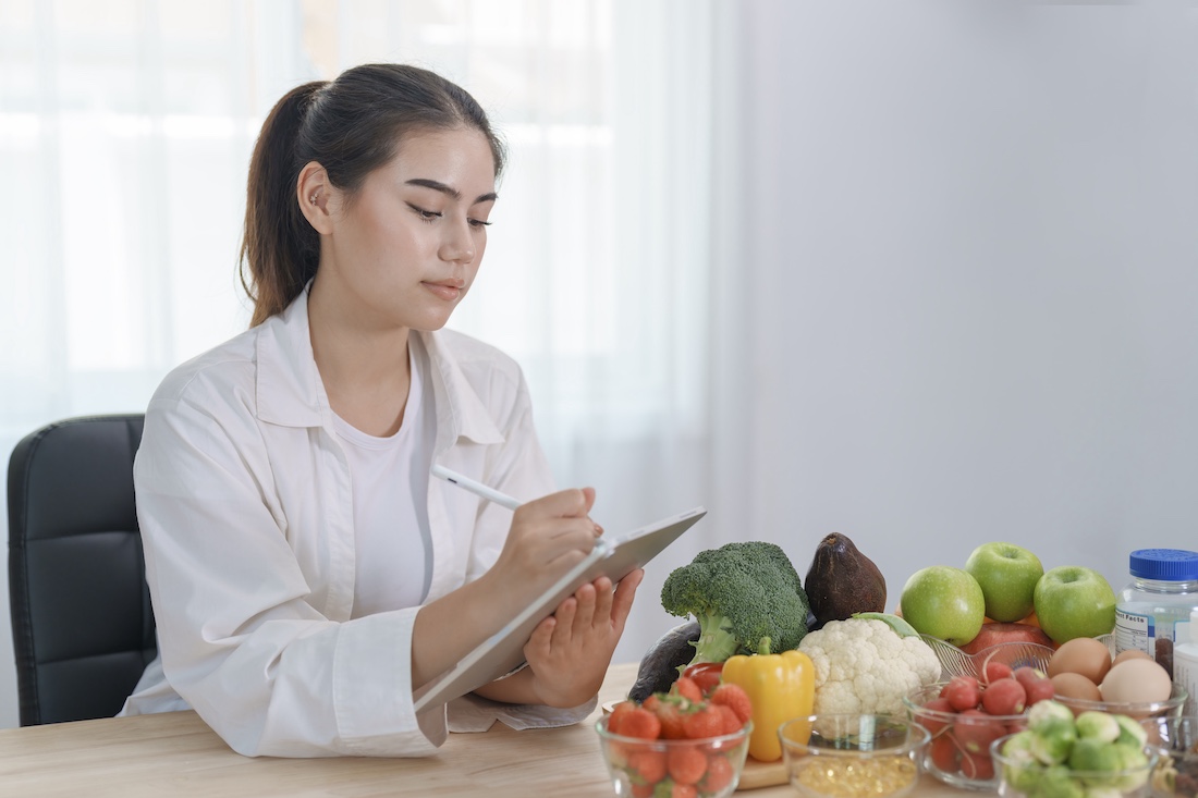 Nutritionist doctor working in office and writing diet plan on tablet