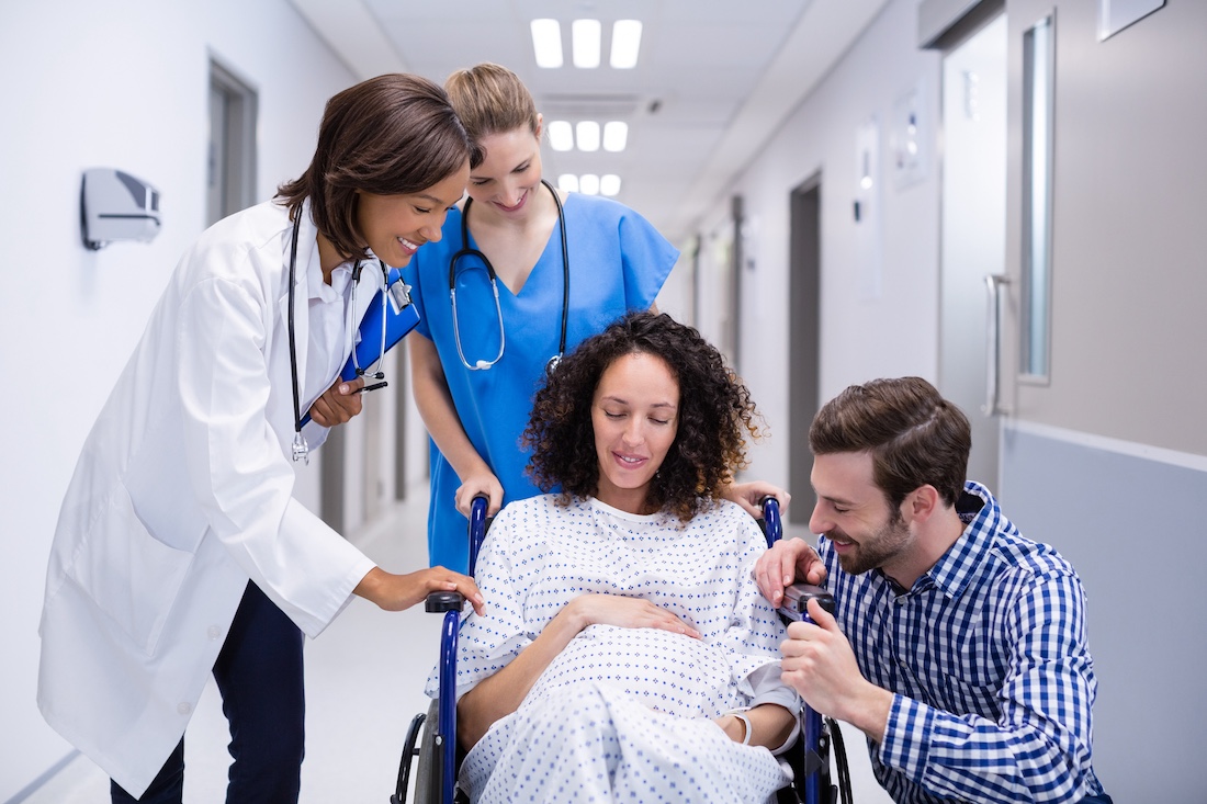 Doctor interacting with pregnant woman in corridor of hospital