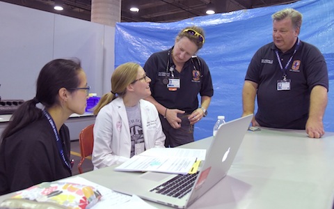 Dr. Raymond Swienton, right, meets with other members of the medical response team at the Mega-Shelter Medical Clinic at Kay Baily Hutchison Convention Center.” width=