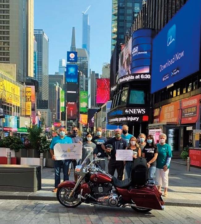 Group of supporters stand behind a motorcycle in Times Square