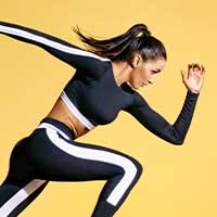 woman wearing black and white fitness apparel in a running pose against yellow background