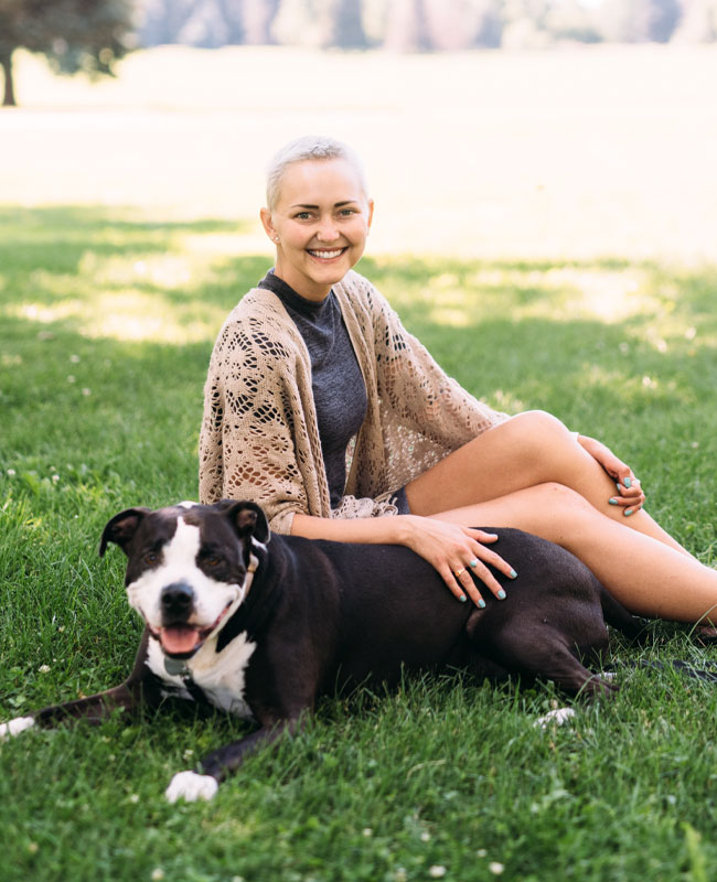 Carley Rutledge young woman relaxes on grass with dog next to her