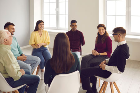 Seven people seated in chairs facing each other in a circle