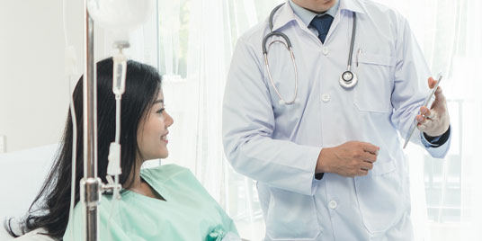 Female patient in hospital bed having a conversation with a doctor