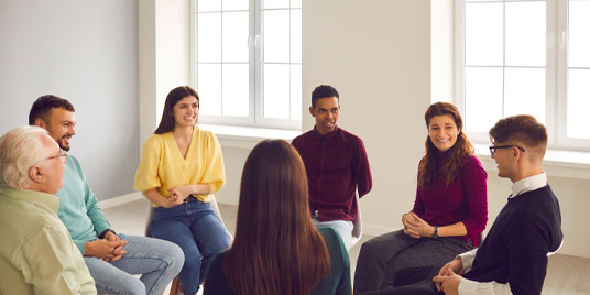 Seven people seated in chairs facing each other in a circle