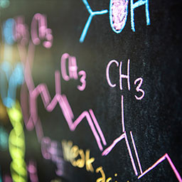 Close-up of chemistry science formula in pink, blue, and yellow chalk on blackboard