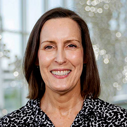 Woman with shoulder-length dark hair wearing black spotted dress