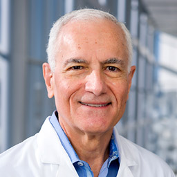 Man with gray hair and glasses wearing white shirt and tie