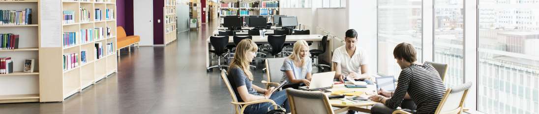 2 women, 2 men students sit at table in library