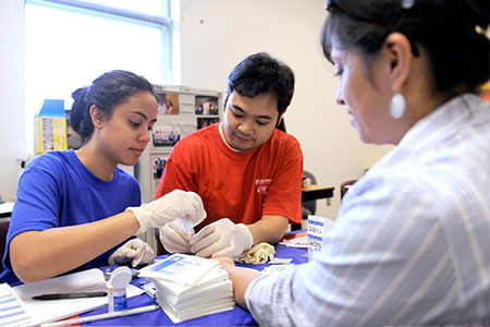 male and female nurses take blood sample from patients finger