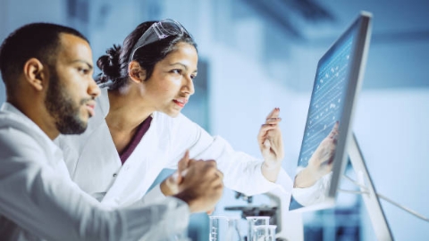 Two scientists, male and female, looking at screen